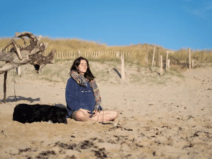 Emeline assise sur le sable, dans une posture d'observation calme